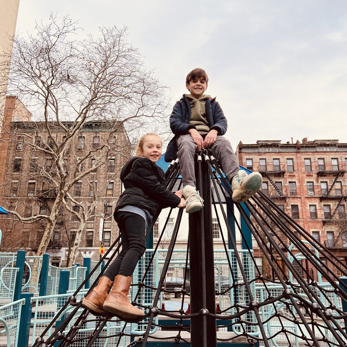 Nina and Lucien climbing a rope pyramid in a Chelsea playground