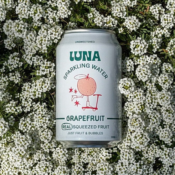 Luna Grapefruit sparkling water can resting in a bed of white flowers